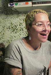 a woman wearing glasses and a gray shirt smiles
