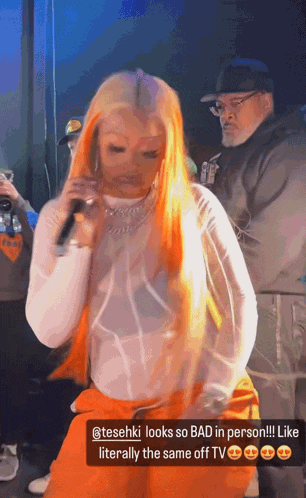 a woman with orange hair is holding a microphone in front of a man