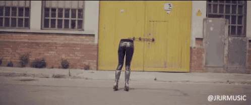 a woman standing in front of a yellow door with jrjrmusic on the bottom