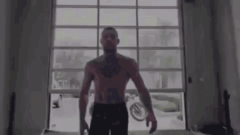 a shirtless man is standing in front of a glass garage door .