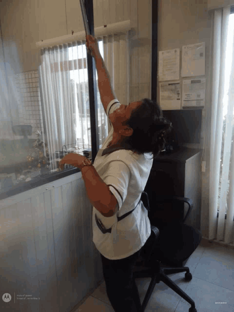 a woman is cleaning a window with a motorola phone