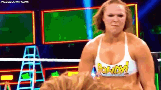 a woman is standing in a wrestling ring wearing a white tank top with the word wow on it .
