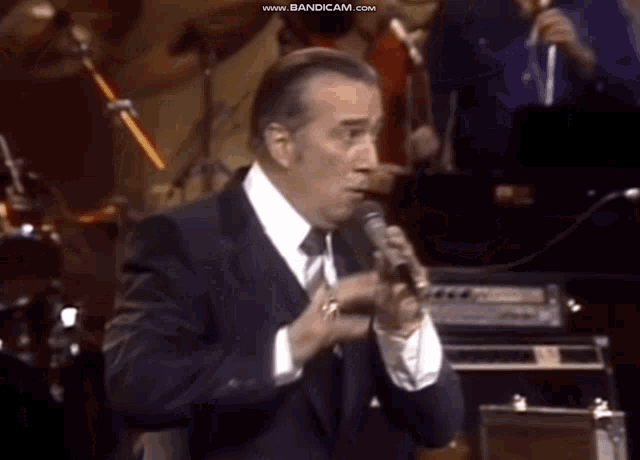 a man in a suit and tie is singing into a microphone .