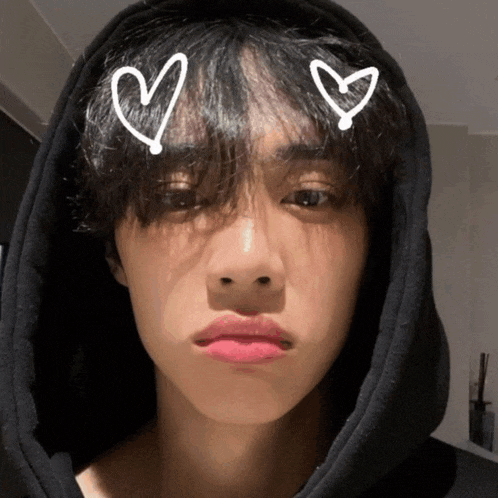 a young man wearing a black hoodie has two hearts drawn on his face
