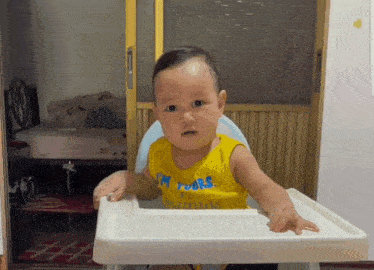 a baby in a high chair wearing a yellow shirt that says i 'm yours