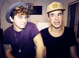 two young men wearing hats are standing next to each other in a room