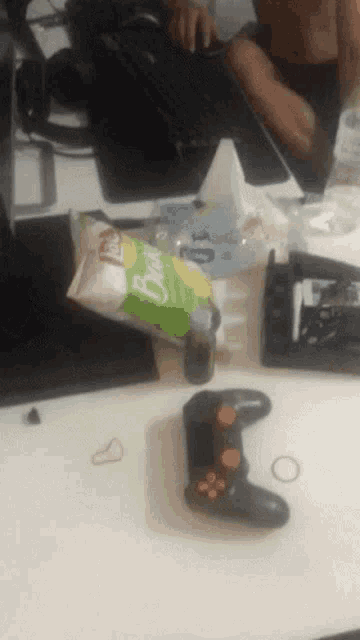 a bag of lays chips sits on a table next to a game controller