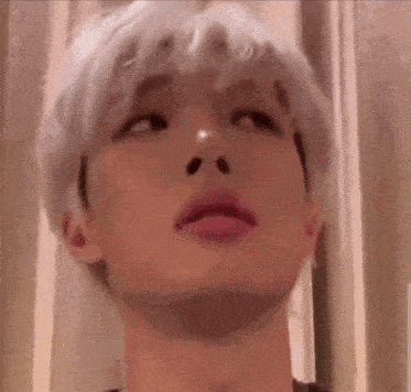 a close up of a person 's face with white hair looking up at the camera .