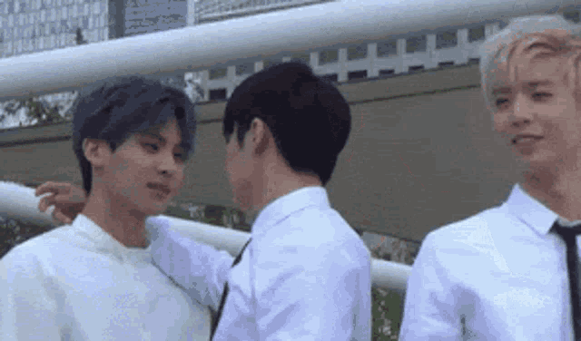 a group of young men are standing next to each other and one of them is touching the other 's neck .