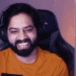a man with a beard is sitting in a chair with his eyes closed and smiling .