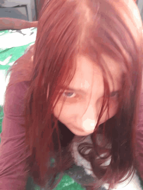 a girl with red hair is laying on a blanket