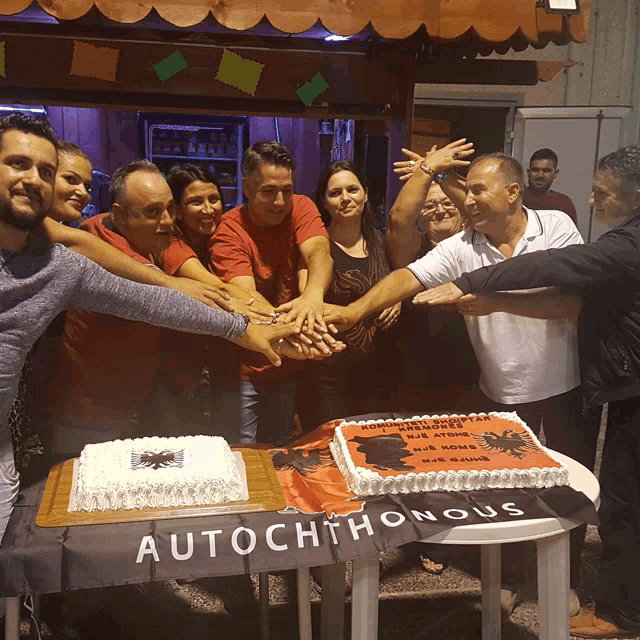 a group of people putting their hands together in front of a cake that says autochthonous on it