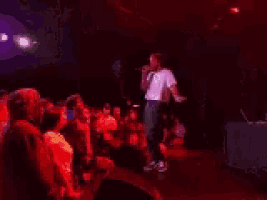 a man is singing into a microphone in front of a crowd