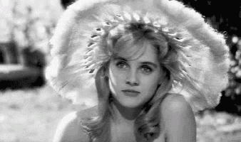 a black and white photo of a woman wearing a hat .