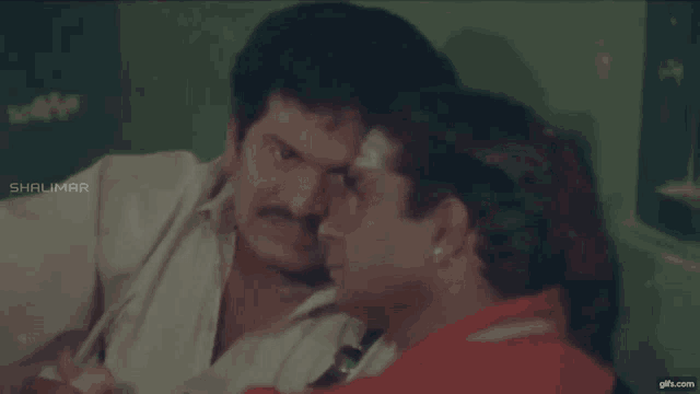 two men sitting next to each other with shalimar on the bottom right