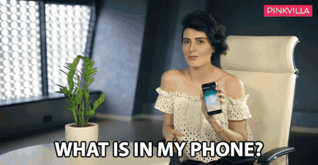 a woman sitting in a chair holding a cell phone with the words " what is in my phone " above her