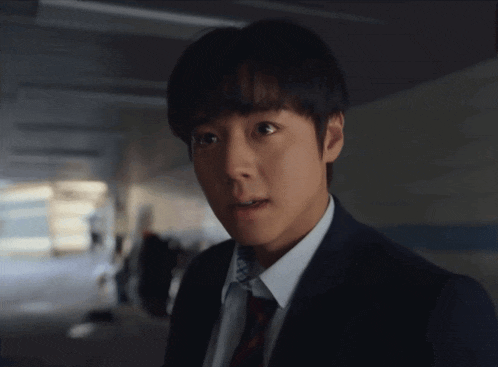 a young man in a suit and tie looks surprised