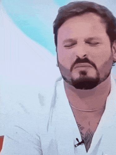 a man with a beard is wearing a white shirt and a microphone on his neck