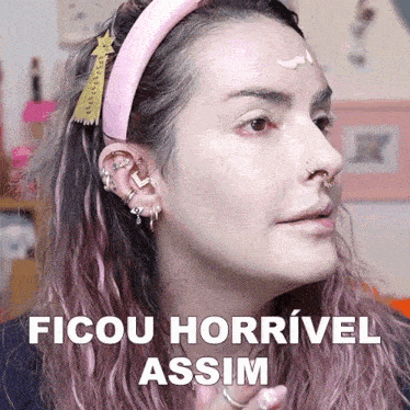 a woman with pink hair is wearing a pink headband and earrings and says " ficou horrivel assim "