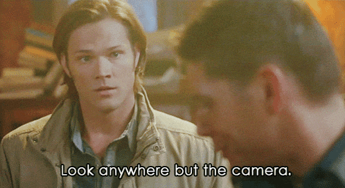 a man says look anywhere but the camera while another man looks on