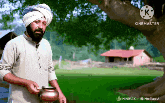 a man wearing a turban is holding a pot in a field with a house in the background
