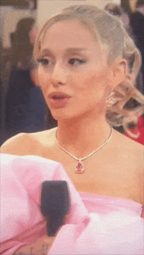 a close up of a woman wearing a pink dress and a pink necklace