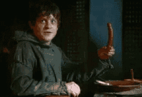 a man is sitting at a table with a sausage in his hand