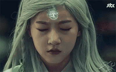a woman with green hair and a diamond on her forehead is crying with her eyes closed .
