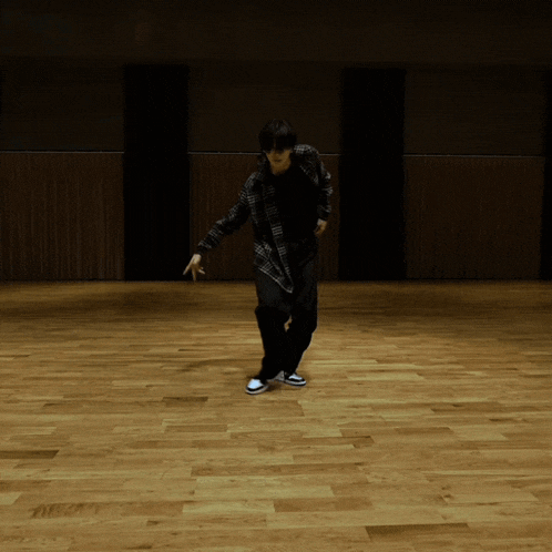 a person in a plaid shirt is dancing on a wooden floor