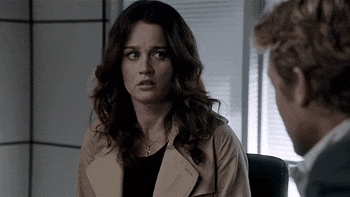 a woman in a trench coat is talking to a man