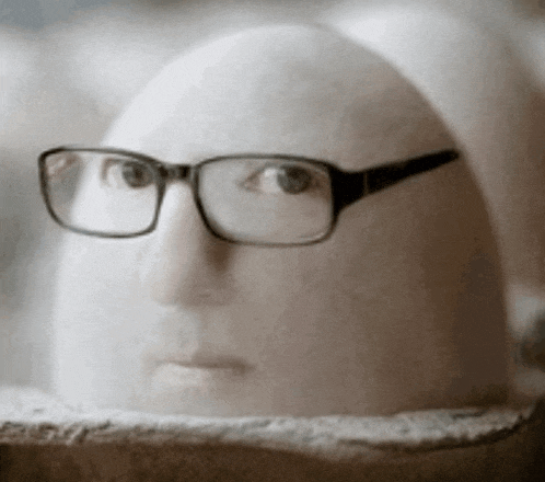 a person wearing glasses is sitting on a rock