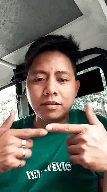 a man wearing a green shirt that says yat jevio is making a funny face