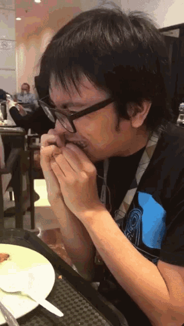 a man wearing glasses is sitting at a table eating