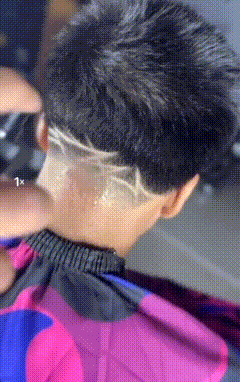 a person is getting their hair cut with a shaved design on the back of their head