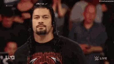 roman reigns is standing in front of a crowd of people .