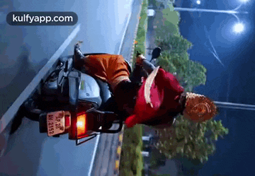 a man is riding a motorcycle down a road at night .