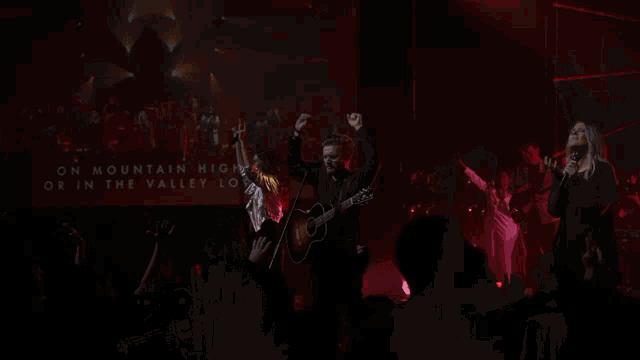 a man in a cowboy hat is playing a guitar in a dark room