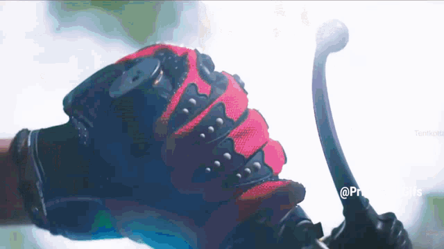 a person wearing a red and black glove is holding a motorcycle brake lever