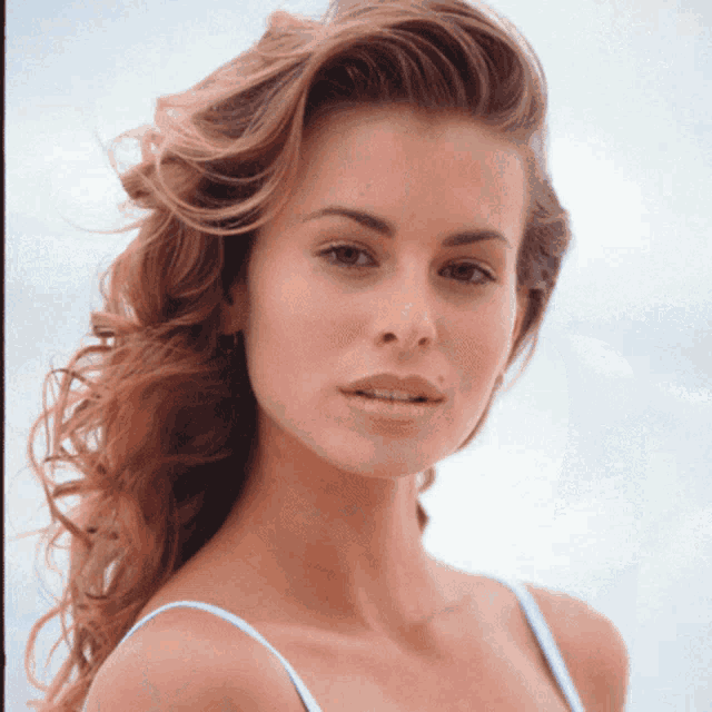 a close up of a woman 's face with a blue tank top on