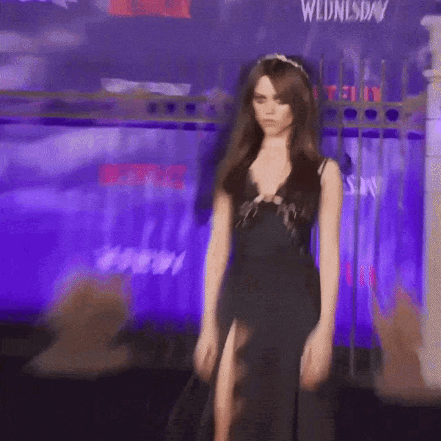 a woman in a black dress stands in front of a sign that says ' day '