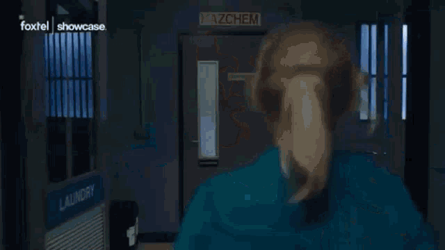 a woman in a blue shirt is holding a gun in a dark room .