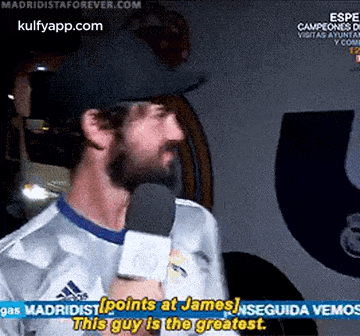 a man is talking into a microphone and says points at james
