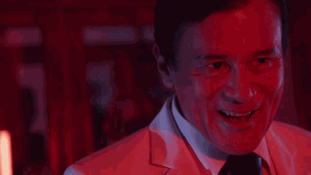 a man in a suit and tie is laughing in a red light