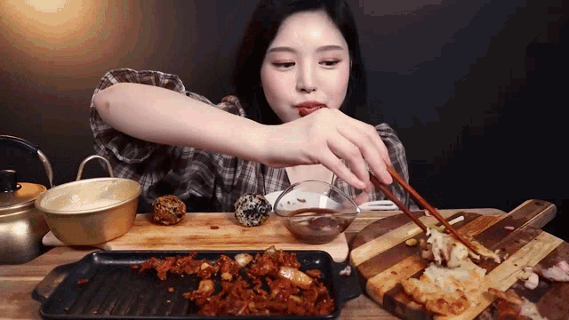a woman eating a meal with chopsticks and a bowl of sauce