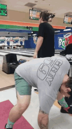 a man in a bowling alley wearing a shirt that says ' i 'm ok ' on it