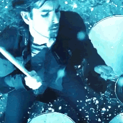 a man in a suit and tie is playing a drum set