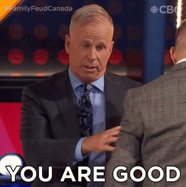 a man in a suit and tie is shaking hands with another man and says you are good