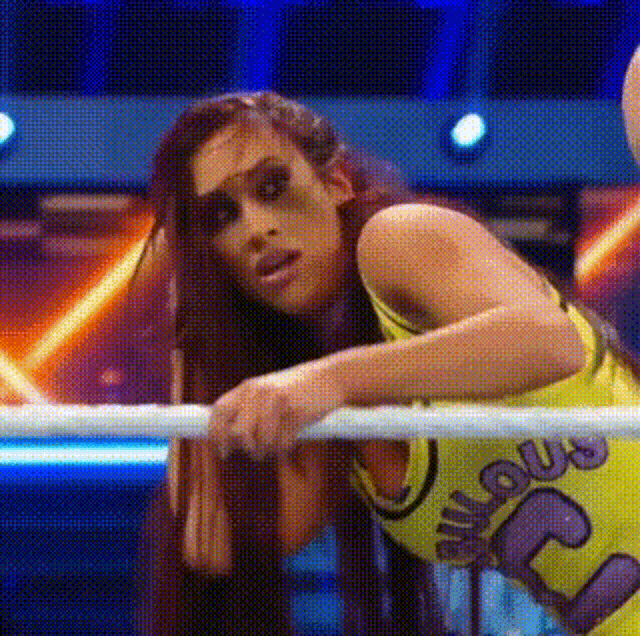 a woman is leaning over a rope in a wrestling ring and making a funny face .