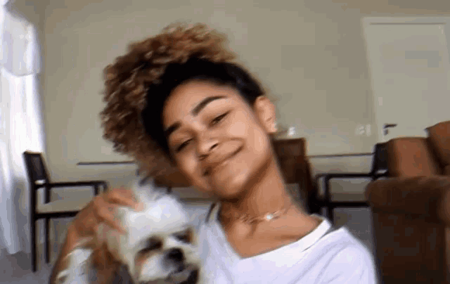 a woman with curly hair is holding a small white dog