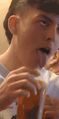 a man is sticking his tongue out while drinking from a cup